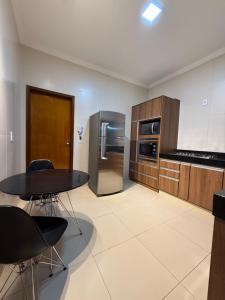 a kitchen with a table and a stainless steel refrigerator at Sua casa em Orlândia in Orlândia +10 photos