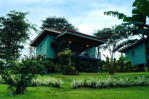 a green house with a balcony in a yard at Cabañas Vista Verde opción con jacuzzi in San Vito