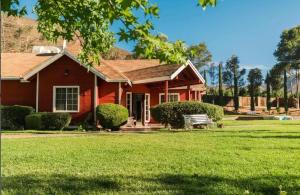 a red house with a lawn in front of it at Baja Vineyard Lodge - Luxury in Valle de Guadalupe with pool in Ensenada