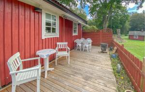a wooden deck with chairs and tables on a house at Cozy Home In Läckeby With Wifi in Bäckebo