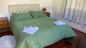 a green bed with two towels on top of it at Pousada Perrone Antiga pousada Marins in Campos do Jordão