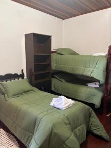 a bedroom with two beds with green sheets at Pousada Perrone Antiga pousada Marins in Campos do Jordão +1 photo