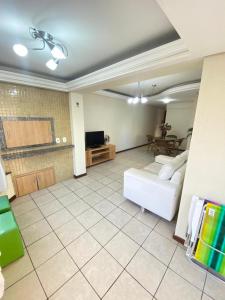 a living room with a white couch and a tv at Apto CAPAO DA CANOA Ed GABRIELA 6 Pers in Capão da Canoa
