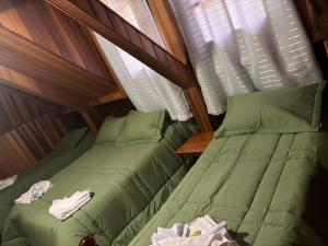 two beds in a small room with windows at Pousada Perrone Antiga pousada Marins in Campos do Jordão
