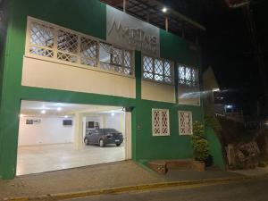 a green and white building with a car parked in the garage at Pousada Perrone Antiga pousada Marins in Campos do Jordão
