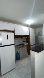 a kitchen with white cabinets and a black counter top at Apto próx a PRAIA in Paulista