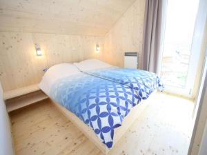 a small bedroom with a bed with a blue and white comforter at Das Edelweiss in Hohentauern