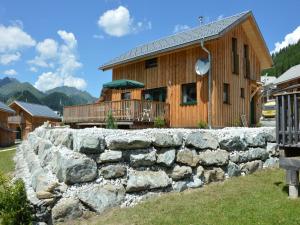a log cabin with a stone wall in front of a house at Das Edelweiss in Hohentauern