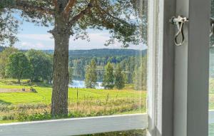 a window with a view of a field and a tree at 2 Bedroom Awesome Home In Töcksfors in Navarsviken