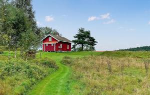 a red barn on a green hill with a dirt road at 2 Bedroom Awesome Home In Töcksfors in Navarsviken +12 photos