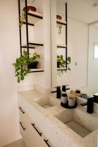 a kitchen counter with two sinks and potted plants at Apartamento Alto Padrão com Vista Para o Lago in Cascavel