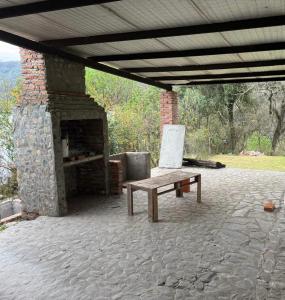 a stone fireplace with a bench and a table at Casa Portezuelo in San Javier