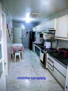 a kitchen with a table and a kitchen with a stove and refrigerator at Casa Dna Nair Gus in Ubatuba