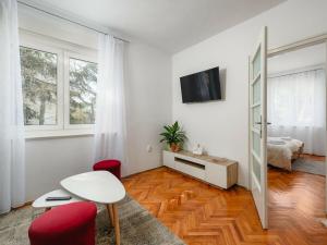 a white living room with a table and red chairs at Apartment Maria in Poreč