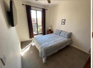 Un dormitorio con una cama con ventana y un televisor. en La Casaita de Marvellita, en Bandita