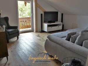 a living room with a couch and a tv at Your holiday apartment Bavarian more in Gstadt am Chiemsee +6 photos