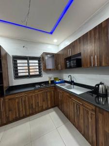 a large kitchen with wooden cabinets and a blue ceiling at Kwamba in Cotonou