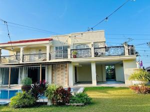 a large house with a balcony and a yard at Villa Kathreyna Private Resort in Alianza