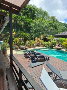 a wooden deck with chairs and a swimming pool at Tehuarupe Surf Studios in Haapiti