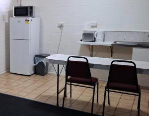 a kitchen with two chairs and a table and a refrigerator at Burdekin Motor Inn in Home Hill
