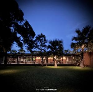 a building with two palm trees in front of it at inchantreemeedao in Ban Chuk Kum