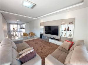 een woonkamer met een bank en een flatscreen-tv bij Casa com 4 quartos com piscina próximo da praia do campeche in Florianópolis