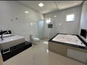 een badkamer met een bad, een wastafel en een toilet bij Casa com 4 quartos com piscina próximo da praia do campeche in Florianópolis +19 foto's