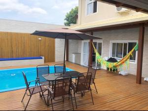 een terras met een tafel, stoelen en een parasol bij Casa com 4 quartos com piscina próximo da praia do campeche in Florianópolis