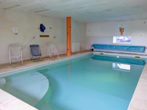 a swimming pool with two chairs in a room at Gîte paisible avec piscine intérieure et animaux acceptés - FR-1-496-132 in Saint-Priest-la-Prugne