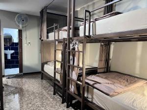 a room with three bunk beds and a bathroom at Chato Hostel in Pakse