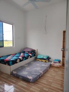 two beds sitting in a room with a window at Saya & Awak Tiny House in Kota Bharu