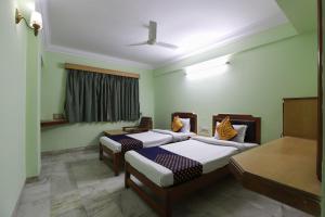 two beds in a room with green walls at SPOT ON Hotel Hilltop in Vadodara