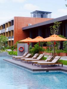 a group of chairs with umbrellas next to a pool at Sunshine Prestige Resort and Spa in Cha Am