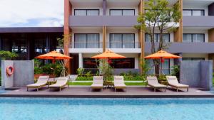 a hotel with chairs and umbrellas next to a pool at Sunshine Prestige Resort and Spa in Cha Am