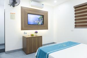 Văn LâmにあるDiện Hoa Homestayの壁にテレビとベッドが備わる客室です。