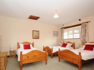 a bedroom with three beds and a window at The Granary in Saint Minver