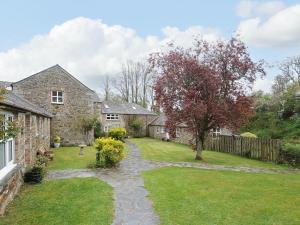 a stone house with a garden and a fence at The Granary in Saint Minver