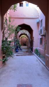 een steegje met een boog in een roze gebouw bij Riad Nahara in Marrakesh