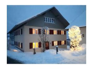 una casa en la nieve con luces encendidas en Holiday Apartment Schwärzler, en Stiefenhofen