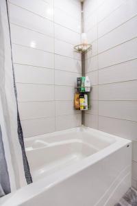 a white bath tub in a white tiled bathroom at 2 min from Bell Center, Downtown & metro station in Montréal +3 photos