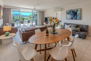 a living room with a table and chairs at Lagoon 004 by HamoRent on Hamilton Island in Hamilton Island