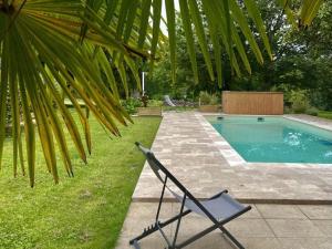 a chair sitting in the grass next to a swimming pool at Grande maison familiale avec piscine chauffée, wifi et parking à Pranzac - FR-1-653-284 in Pranzac