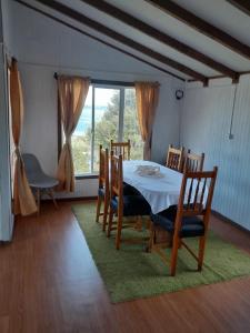 a dining room with a table and chairs and a window at Cabaña Muñoz Navarro in Huildad