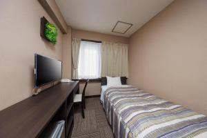a hotel room with a bed and a flat screen tv at Mizusawa Green Hotel in Oshu