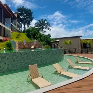a swimming pool with two chairs and a swimming poolvisorvisor at Apartamento vista mar, Luar do Morro, Amerigo 215 MORRO DE SAO PAULO in Morro de São Paulo