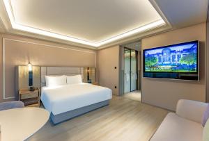 Un dormitorio con una cama blanca y un televisor de pantalla plana. en Mercure Shanghai Lujiazui, en Shanghái