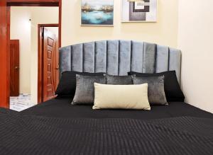 1 dormitorio con 1 cama grande y cabecero gris en Versace Homes in heart of DHA, en Karachi