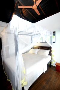 a bedroom with a white bed with a ceiling at Ocean Soluna Beach Villa in Tangalle