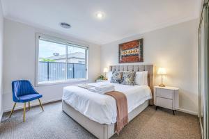 a bedroom with a bed with a blue chair and a window at StayAU Newly 8 Beds Spacious Home in Derrimut in Derrimut