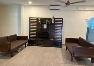 a living room with two couches and a flat screen tv at D'Lima Beach Inn in Pantai Cenang